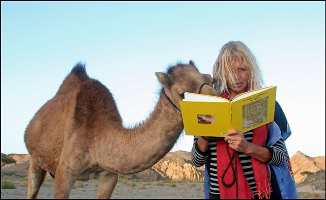 Karen leest een boek samen met een nieuwsgierige dromedaris